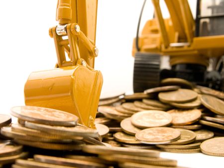Yellow excavator digging a heap of coins isolated over white backgroundの写真素材
