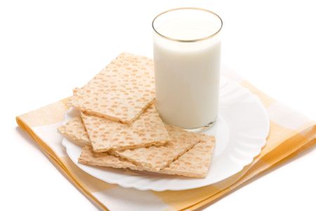 Glass of milk and dish of crackers over table-napkin isolated on white backgroundの写真素材