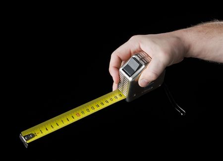 Measuring tape in hand. Isolated on a black background.の写真素材