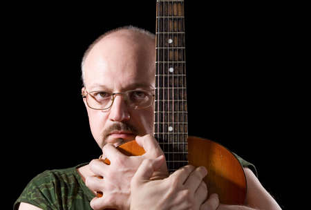 Portrait of the man with an acoustic guitar on a black backgroundの写真素材