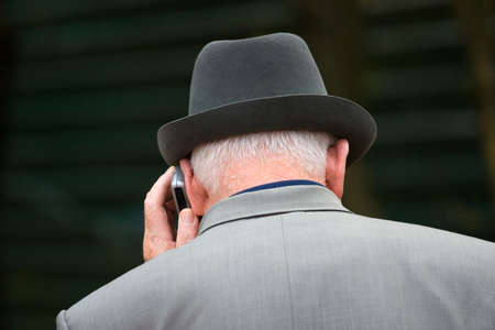 Old man in a hat talks by a mobile phoneの写真素材