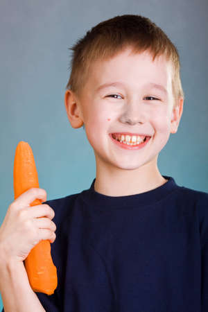 eight years old boy with fresh carrotの写真素材