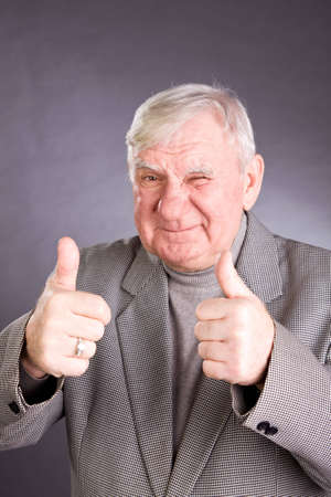 senior man showing thumb up on a grey backgroundの写真素材