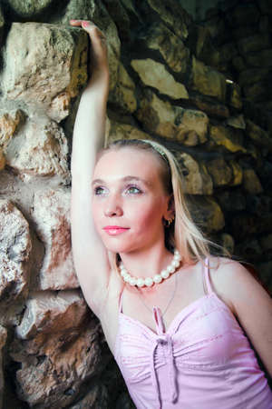 Beautiful young woman on a background of stone wallの写真素材