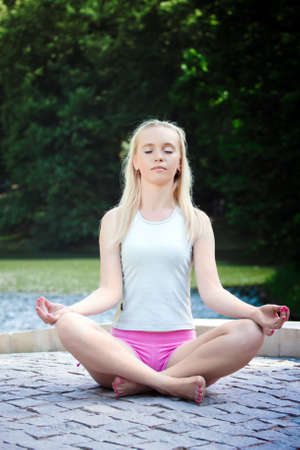 Pretty young girl sitting in lotus positionの写真素材