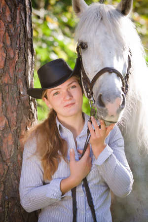 Young Lady in hat hugging her horseの写真素材