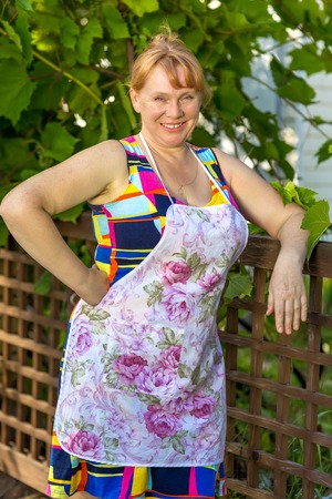 Rural women in an apron standing at fenceの写真素材