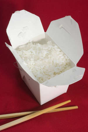 chinese take out rice with chopsticks on red table clothの写真素材