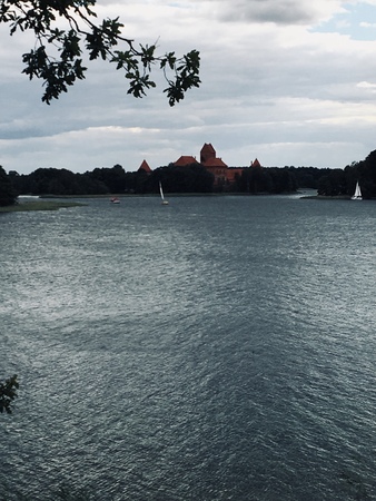 Trakai Historical National Park,   heritage site, on summer day. Trakai Island Castle, a major tourist attraction, reflecting in clear water of Galve lake. Couple on catamaran swimmingの写真素材