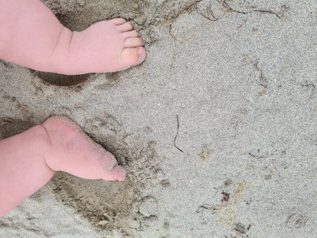 Baby's feet on the sand at the beach in the summer.の写真素材