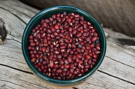Red adzuki beans in a bowl on a wooden background.