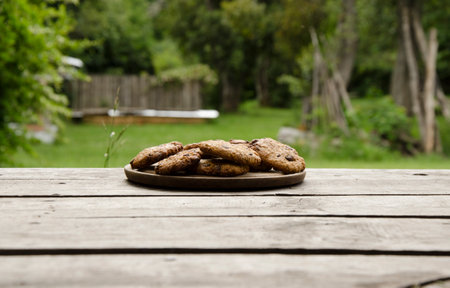 Chocolate chip cookies on rustic wooden table in the garden.