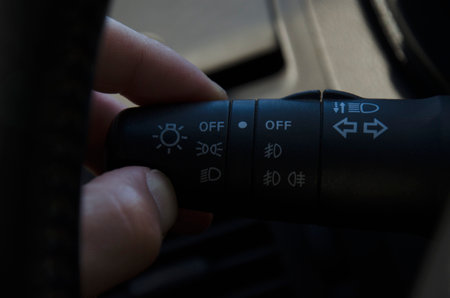 hand activating the knob of the lights of a car, with indicator of high, low, position and turn...