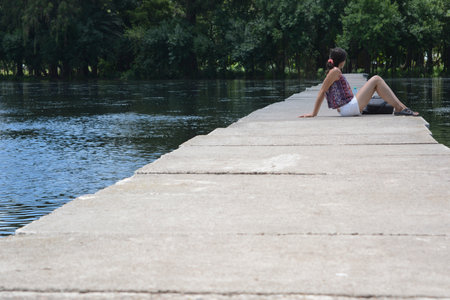 woman sunbathing on a footbridge by a lake, in the park in the center of the city of 9 de julio in...