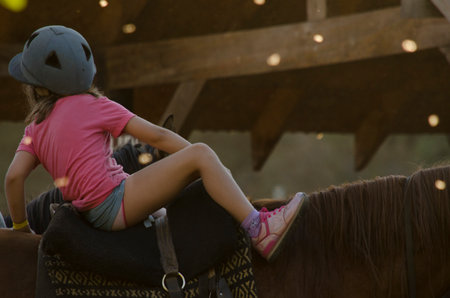 girl dressed in pink getting on a horse. wearing a helmet ready for a horse rideの写真素材