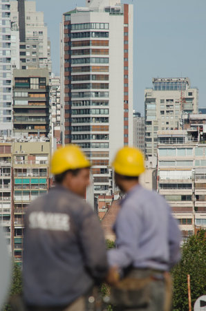 construction workers out of focus with the city in the background, wearing work clothes at height