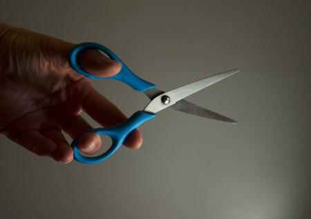 hand taking scissors for trimming, blue-colored scissors of two silver blades with edge