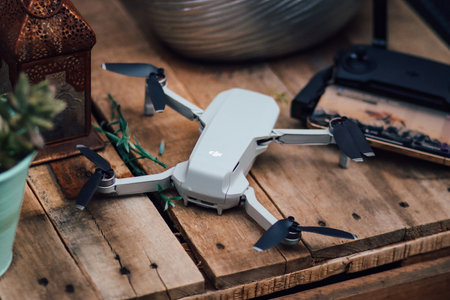 Drone quadcopter with digital camera controller on a wooden table.