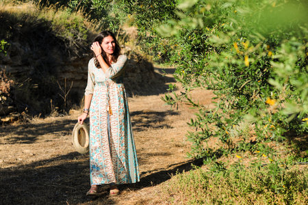 Beautiful young woman walking in the olive grove on a sunny dayの写真素材
