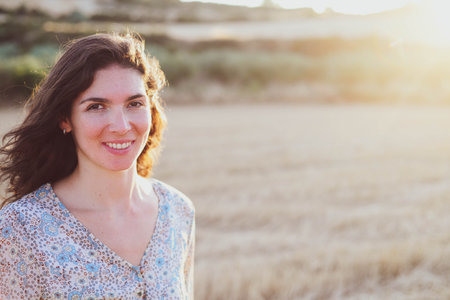 Portrait of a beautiful woman in a wheat field at sunset.の写真素材