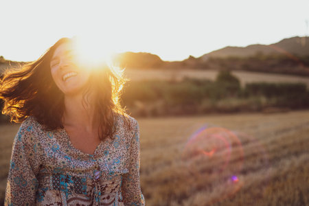 Portrait of a beautiful woman enjoying the sun in a wheat fieldの写真素材