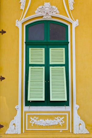the closed green window on the yellow wall の写真素材