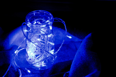 Garland in a jar in a rug. Glowing light bulb garland