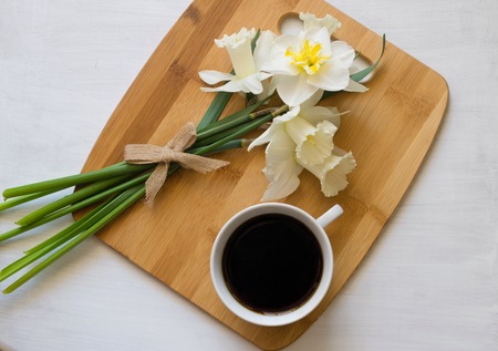 Morning coffee and daffodils on a wooden board.の写真素材
