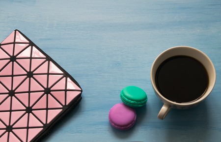 Cosmetic bag, cup of coffee, macaroons on blue background