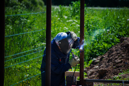 Welder working a welding metal. A man is welding a metal fence. Welder.