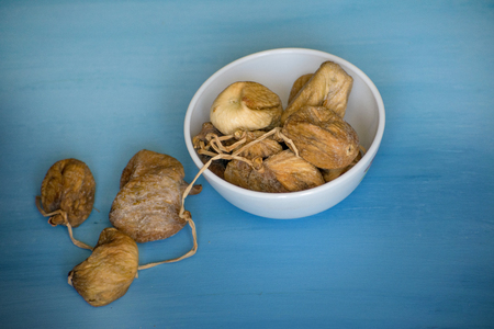 Dried figs in a white bowl on a blue table.の写真素材