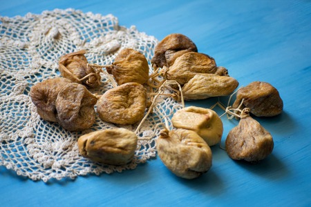 Bunch dried figs on on a knitted napkin on a blue table.の写真素材