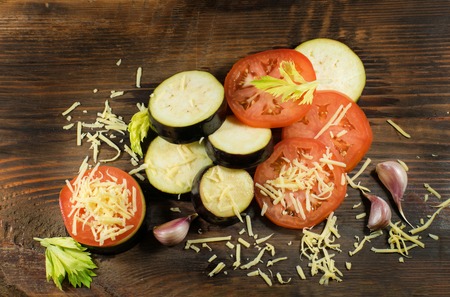 Sliced eggplant and tomato. Tomatoes, aubergines, cheeses, garlic and celery on a wooden board.の写真素材