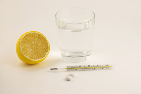 Hot tea with lemon, tablets and thermometer on white background. Healthy concept.の写真素材