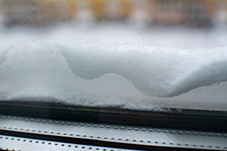 Snow close-up lies on the windowsill outside. Snow on the windowsill, snow-covered window.の写真素材