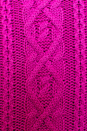 Knit texture of magenta wool knitted fabric with cable pattern as background.