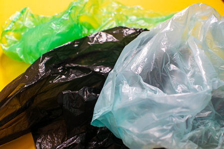 A lot of colorful plastic bags on yellow backgroundの写真素材