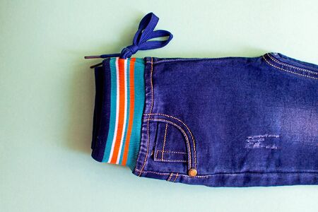 Children's blue jeans for boys on light green background. Top view.