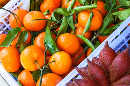 Fresh tangerine clementine with green leaves. Tangerines in a box in the supermarketの写真素材