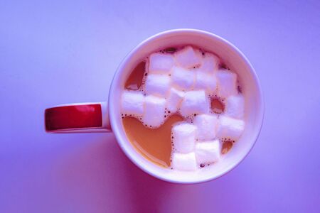 Delicious hot coffee with marshmallows in mug in neon light, top view. Warm autumn and winter mood.の写真素材