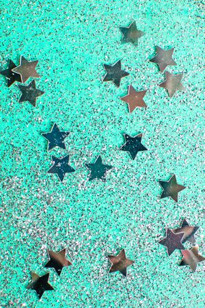 Splash of silver sparkles and stars on mint background. Blurry image. Selective focus.の写真素材