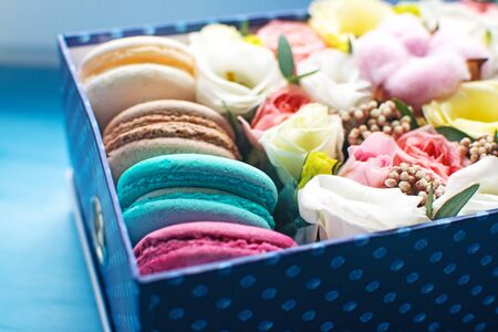 Blue box of tender flowers and bright macarons. Romantic gift for your beloved woman. Selective focus.の写真素材