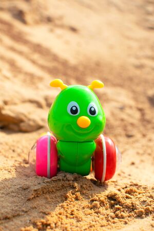 Bright green caterpillar toy in the sandbox. Funny children toy.の写真素材