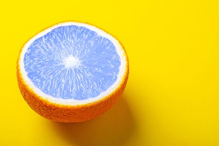 Half of classic blue orange close-up on a bright yellow background. Juicy summer concept with copy space. Orange like a swimming pool.の写真素材