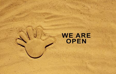 End of quarantine. Text message W are open on the sand. Welcome sign on the beach. Hotel, cafe, beach, travel service owner welcoming guests after coronavirus outbreak.の写真素材