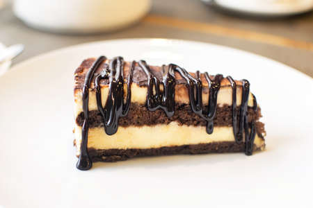 Slice of tasty chocolate tiramisu on white plate on table in cafe. Traditional Italian biscuit dessert or cake.の写真素材