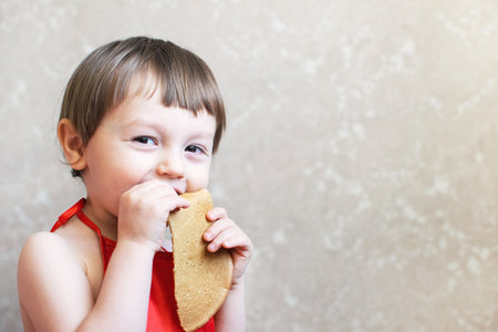 Little happy boy eating pancakes with his hands. Delicious pancakes.の写真素材