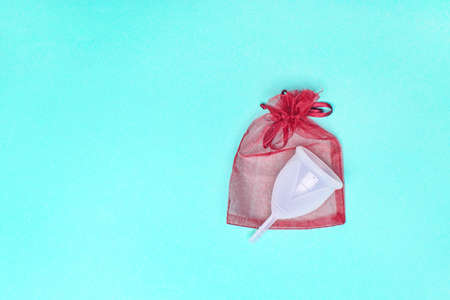 Eco-friendly siliconemenstrual cup with red package on green background.の写真素材
