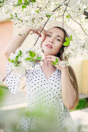 Beautiful girl posing in a park or garden near a blooming apple and cherry tree.の写真素材
