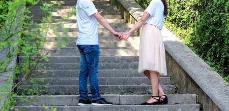 Young couple in love at the rest on the nature. man and woman outdoors. legs closeup. hands together. close up. stairs on backgroundの写真素材